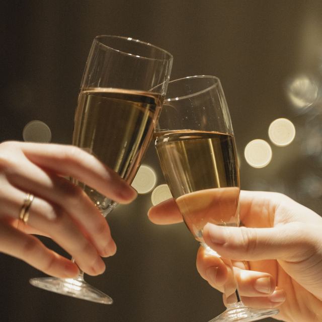 Close-up of two champagne flutes being clinked together in a warm, low-lit room