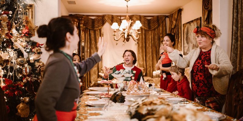 A long family table mid-meal at Christmas, everyone laughing at one end of it