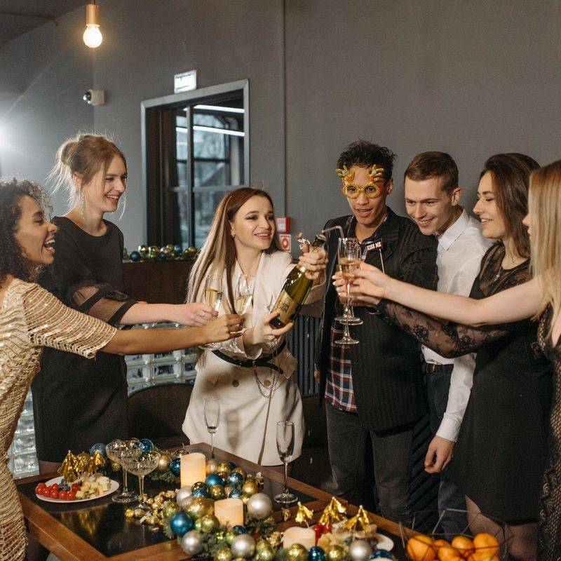 Colleagues reaching in to clink glasses over a table of baubles at a Christmas party