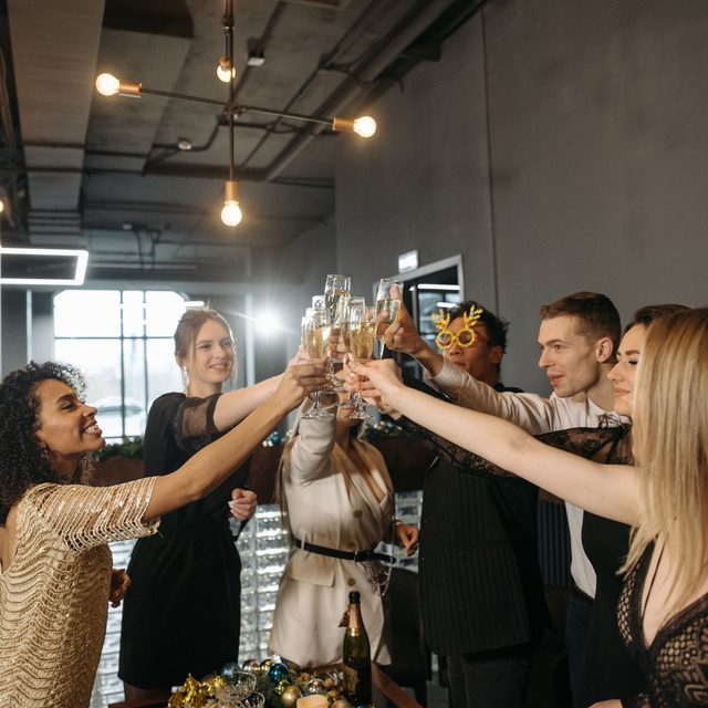 A circle of arms raising champagne flutes together at a Christmas party