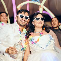 A newly married couple in novelty sunglasses covered in confetti at their party