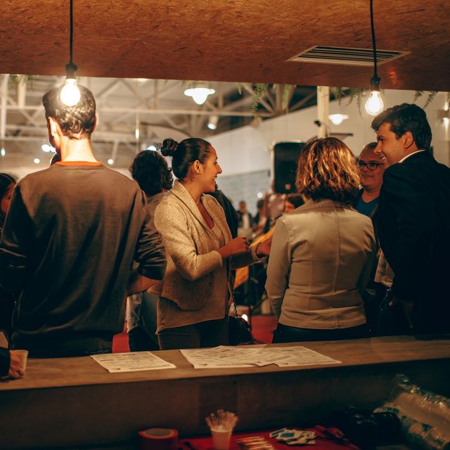 Guests standing with drinks at a crowded evening networking event