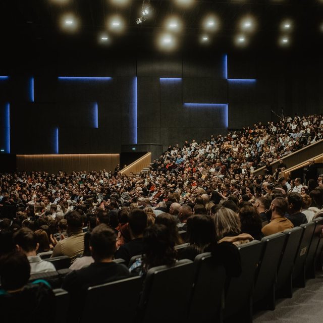 Rows of seated delegates filling a darkened conference hall