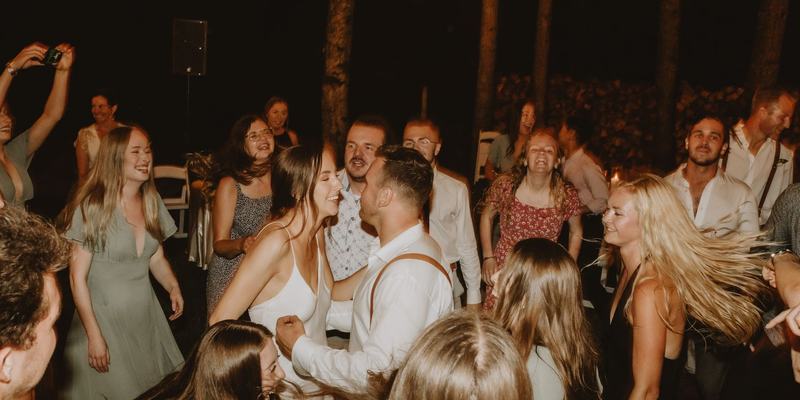 Blurred motion of guests dancing outdoors at night at a wedding reception