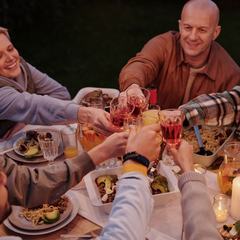 Adults and children clinking glasses at an evening table in a garden