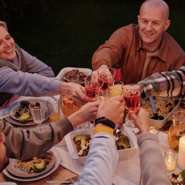 Adults and children clinking glasses at an evening table in a garden