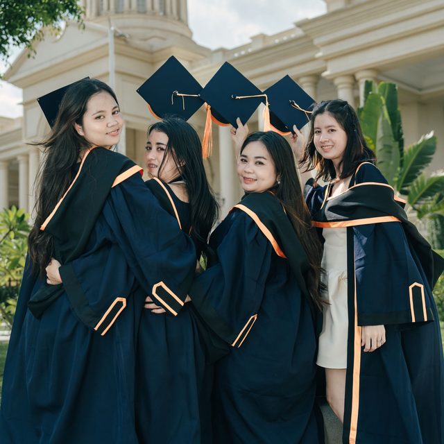 Graduates in navy gowns holding on to each other outside the ceremony