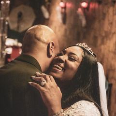 Newlyweds holding each other close during their first dance in warm low light