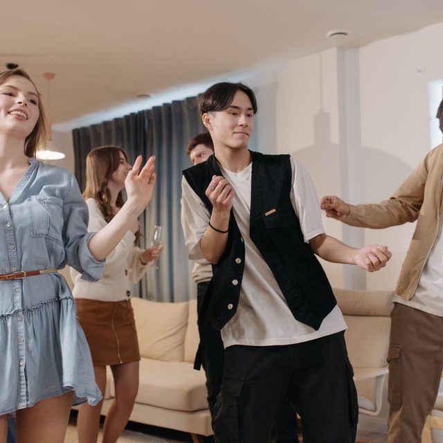 Friends dancing together in a living room with the furniture pushed back