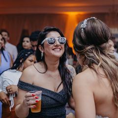 Guests dancing with drinks in hand under warm orange lights at a wedding reception