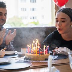A dim, grainy snapshot of a woman blowing out birthday candles in a restaurant