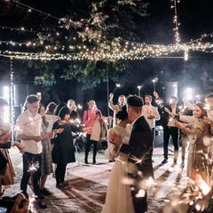 A couple dancing outdoors while guests hold sparklers around them